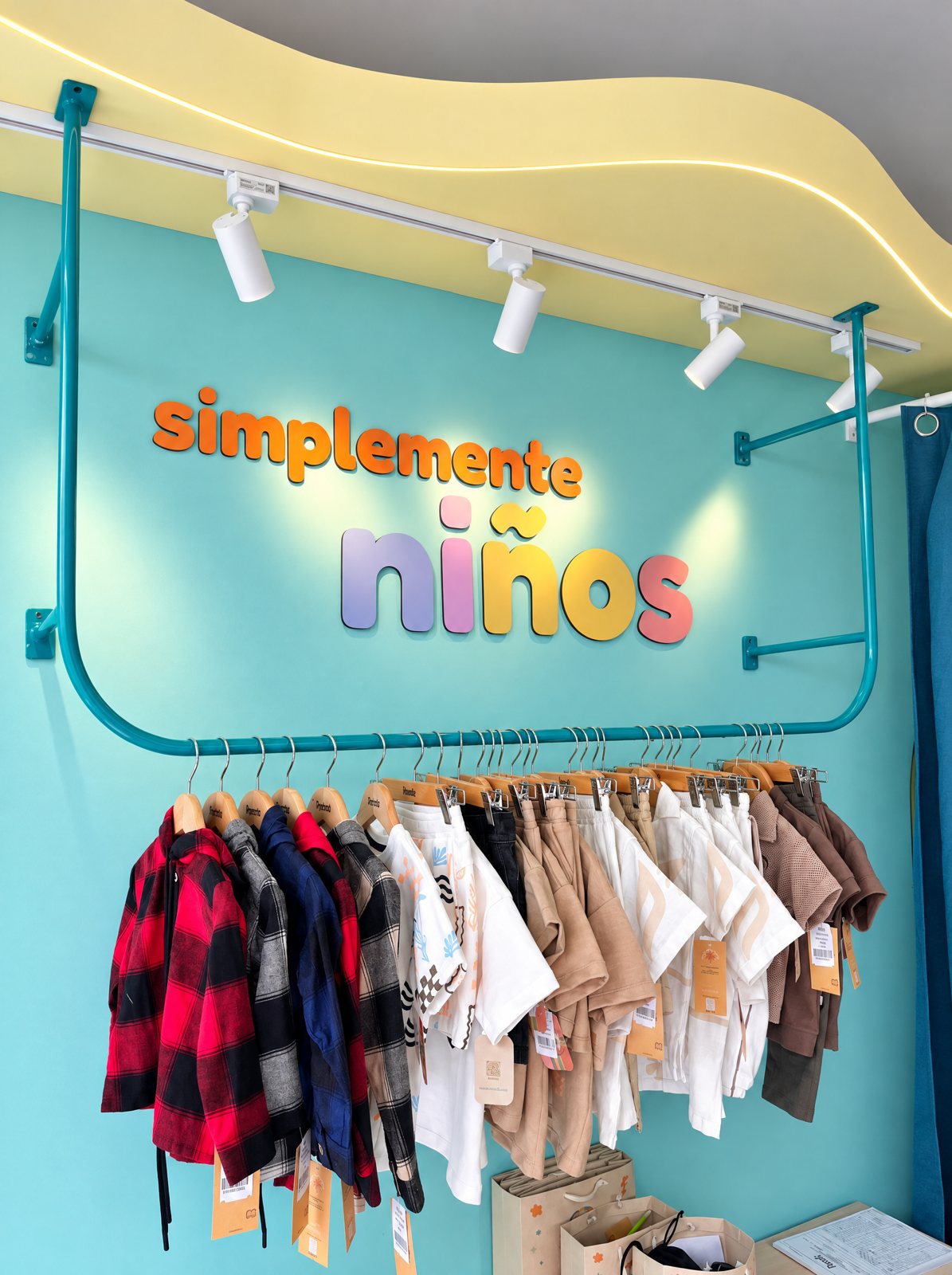 Letrero simplemente niños sobre el perchero turquesa con ropa infantil
