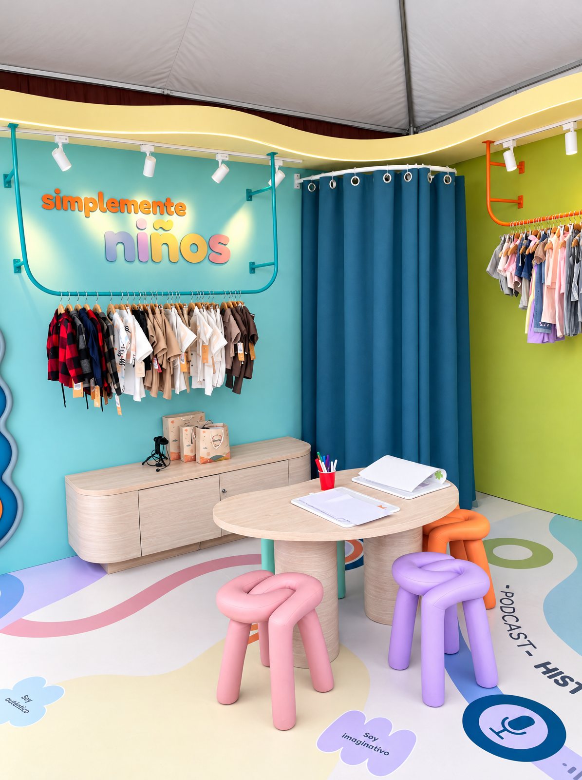 Vista general del stand con el letrero simplemente niños y la mesa con banquitos de colores
